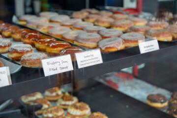 shallow depth of field focus on an assortment of donuts or doughnuts in a pastry shop window