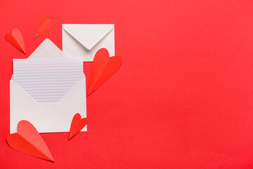 Envelopes with blank card and paper hearts on red background. Valentine's Day celebration