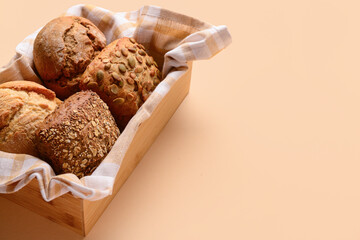Box with different delicious buns on beige background