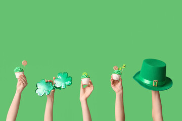 Female hands with tasty cupcakes, leprechaun hat and plastic eyeglasses for St. Patrick's Day on...