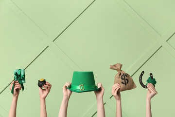 Female hands holding gift box and party decor for St. Patrick's Day celebration on green background