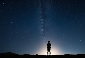 Fototapeta premium Man gazing at the celestial heavens in the darkness of the night 