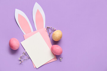 Blank card with bunny ears made of paper, Easter eggs and beautiful gypsophila flowers on lilac background