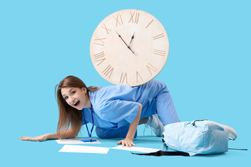 Female medical intern with big clock on blue background
