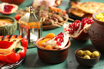 Traditional Eastern dishes and Muslim lantern on green table, closeup. Ramadan celebration