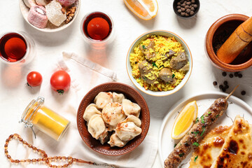 Traditional Eastern dishes and prayer beads on white table. Ramadan celebration