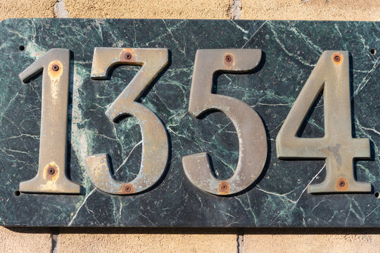 tarnished brass numbers 1354 on green marbled stone