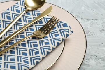 Clean plates, cutlery and napkin on light grey textured table, closeup