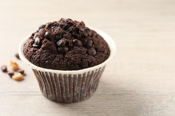 Delicious chocolate muffin on white wooden table, closeup and space for text