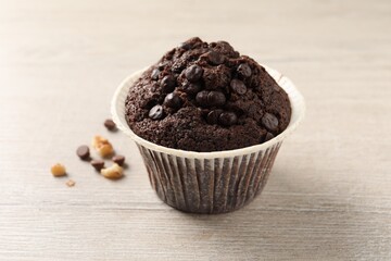 Delicious chocolate muffin on white wooden table, closeup