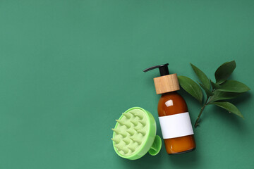 Hair scalp massager with bottle of shampoo and leaves on green background
