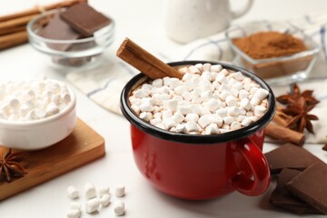 Tasty hot chocolate with marshmallows and ingredients on white table, closeup