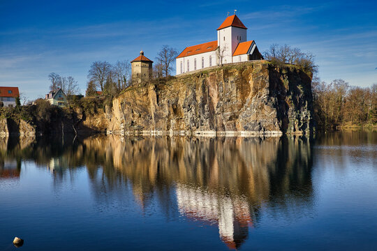 Dorfidylle in Beucha: Die historische Bergkirche und der markante Wasserturm thronen auf der Porphyrwand &uuml;ber dem spiegelglatten Kirchbruch, Sachsen, Deutschland
