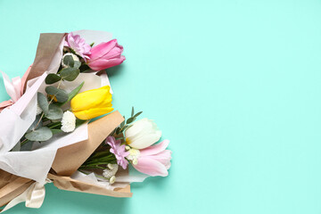 Mini bouquets of beautiful spring flowers in wrapping paper on turquoise background. International Women's Day