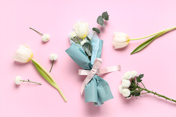 Composition with mini bouquet of beautiful spring flowers in wrapping paper on pink background....