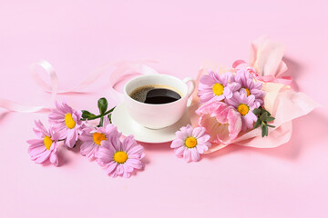 Obraz na płótnie Canvas Mini bouquet of beautiful spring flowers in wrapping paper with cup of coffee and ribbon on pink background. International Women's Day