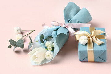 Mini bouquet of beautiful spring flowers in wrapping paper with gift box on pink background....