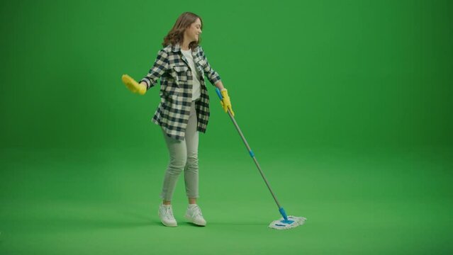 Green Screen.A Smiling Young Woman Housewife in Yellow Rubber Gloves is Washing the Floor with a Mop and Dancing. Virtual Consultations for Appliance Cleaning. Cleaning Hacks for Specific Appliances.