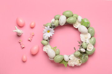 Easter wreath with white flowers, eggs, butterflies and bunny figurine on pink background