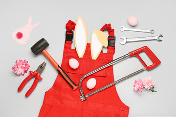 Composition with constructor's tools, uniform and Easter decor on grey background