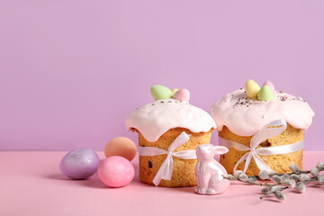 Composition with delicious Easter cakes, porcelain bunny and painted eggs on color background