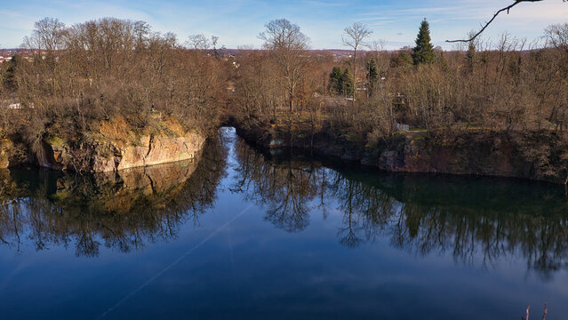 Spiegelung der steilen Porphyr-Felsw&auml;nde in der engen Passage des Steinbruchsees Beucha unter blauem Himmel, Brandis, Sachsen, Deutschland
