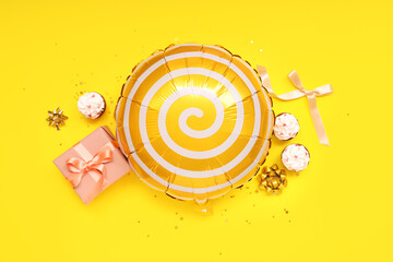 Balloon with gift box and cupcakes on yellow background