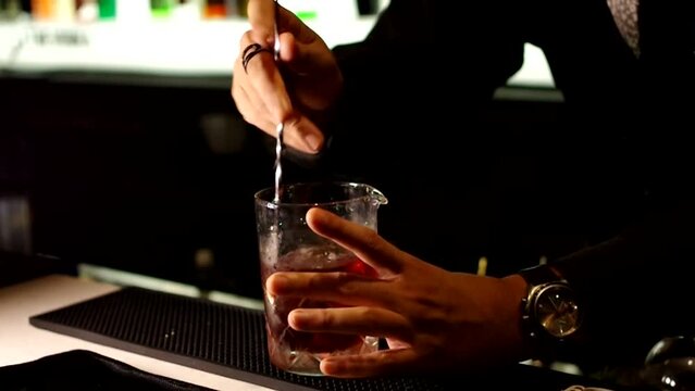 Bartender stirring cocktail negroni at bar counter