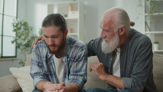 Family conversation on the couch: young and elderly men talk about life, psychological support for each other, cross-generational dialogue, heartfelt consolation, advice and wisdom, warm communication