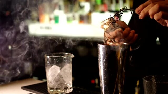 bartender burning rosemary with butane torch rosemary-smoked negroni cocktail making video