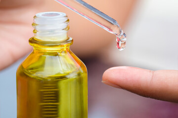 hands of a beautiful woman Dropping serum collagen moisturizer of face into clear yellow bottle soft light background. Protector skin Treatment facial essence oil, Vitamin C. Beauty and spa Concept	
