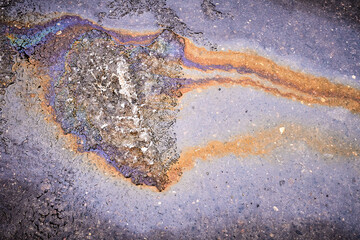 A bright spot of oil or gasoline splash on the asphalt after the snow melts