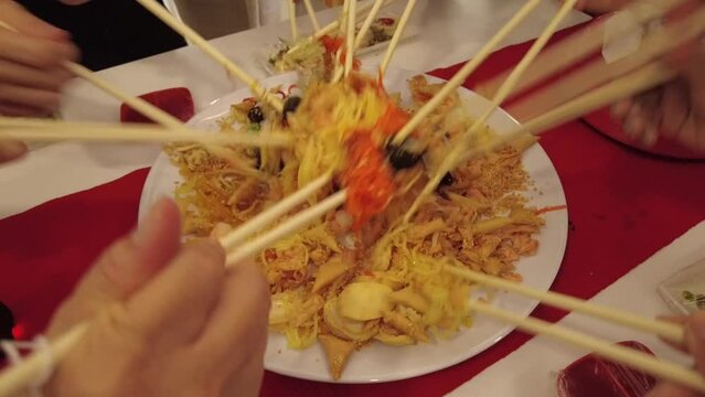 Close up of lo hei, or the Prosperity toss of a dish of Cantonese-style raw fish salad during Chinese New Year celebration. Family and friends gather for this to bring good luck and fortune