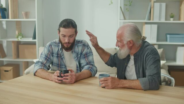 Two friends, a young man and an older man, are sitting at a table, discussing life situations and providing each other with psychological support, friendly communication, intergenerational dialogue