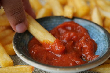 detail shot of French Fries sipping sauce on table 