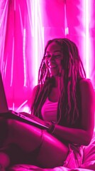 African American girl sitting with laptop on bed at night