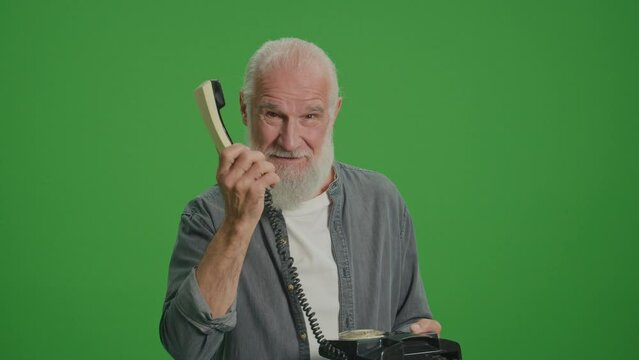 Green Screen.Portrait of an Old Man Showing How to Use a Vintage Telephone.An Elderly Man Proves the Convenience of a Vintage Telephone and Shows a Thumbs Up.Simplicity of Use for Senior Phones.