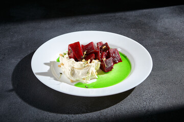 Gourmet beetroot salad with stracciatella cheese, pine nuts, and vibrant green sauce