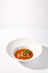 Classic Italian style tomato soup with seafood on white, suited for gourmet blogs and cookbook illustrations