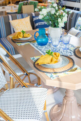 Plate setting with yellow handkerchief on wood table with artificial flowers on the dining table.