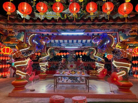 The image shows a brightly lit temple decorated with colorful lanterns and dragon statues.