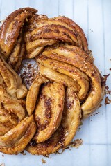 Roscón de reyes Kringle Estonia. Braided sponge cake with cinnamon, butter, walnuts or almonds and icing sugar on a rack and white baking paper.