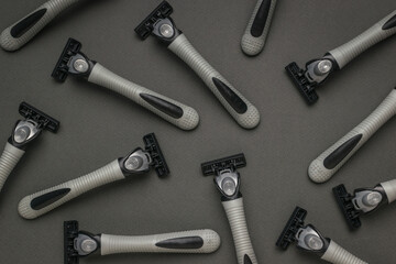 Several grey men's razors on a grey background.