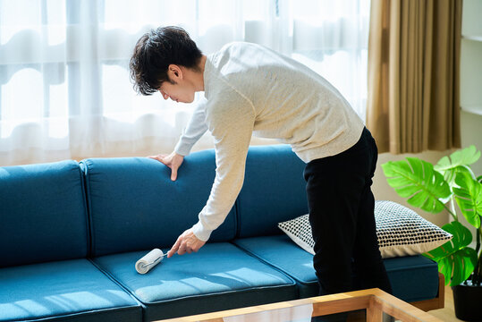 ソファーの掃除をする若い男性