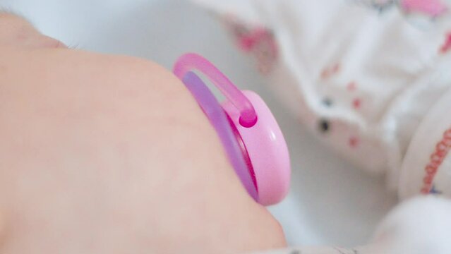 Newborn tranquility with a subtle pink pacifier resting alongside, highlighting moments of infancy peace.