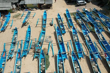 Blue fishing boats anchored on the shore. White sandy beach with blue turquoise crystal sea water. 