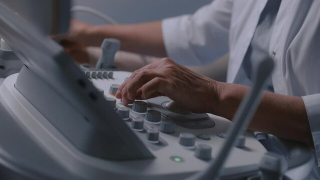 Close up of doctor using ultrasound machine. Professional medic does abdominal organs sonography check up and examination to female patient. Modern clinic or hospital with advanced medical equipment.