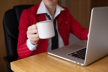 Close up of business woman hands with laptop holding coffee cup in the office. 