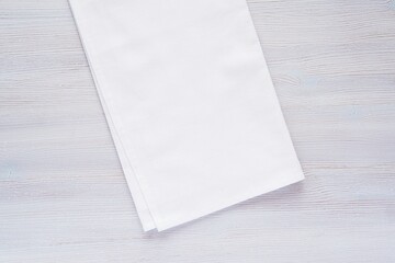 White plain fabric kitchen towel or tea towel folded on wooden background, mockup for design presentation, close up view.