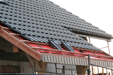 Installation of graphite roof tiles on wooden beams, a breather and waterproofing membrane, grey...